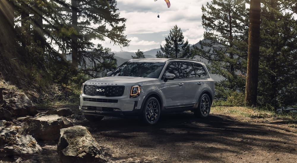 A grey 2022 Kia Telluride parked in the woods with a view of the mountains.