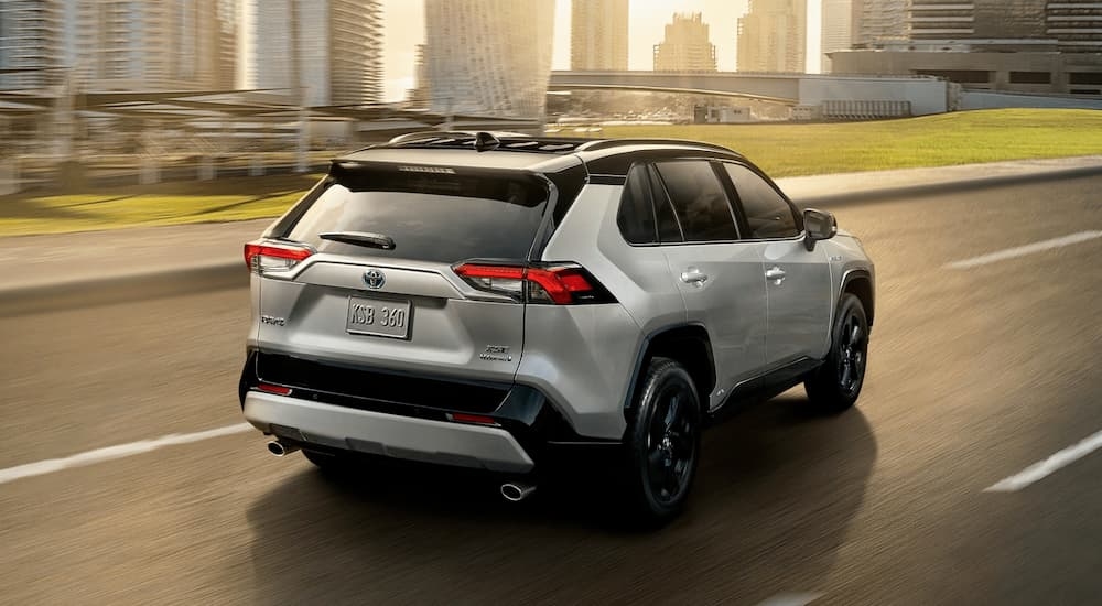A silver 2020 Toyota RAV4 XSE is shown driving towards a city.
