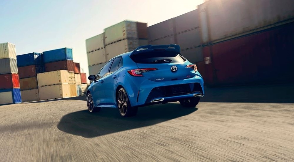 A blue 2020 Toyota Corolla XSE is shown from the rear driving past shipping containers