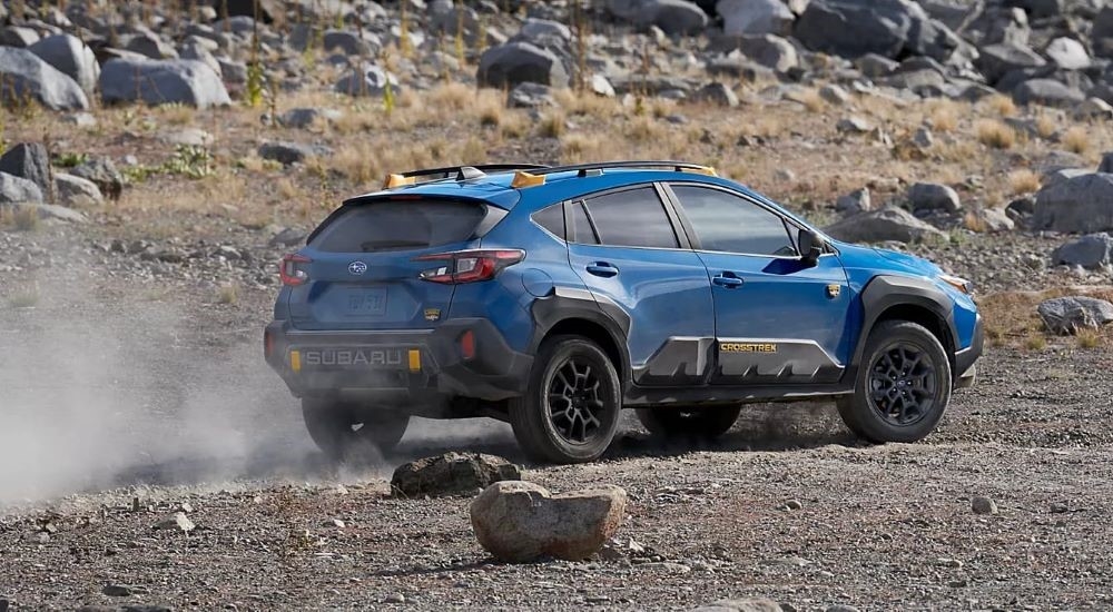 A blue 2024 Subaru Crosstrek Wilderness is shown kicking up dust.