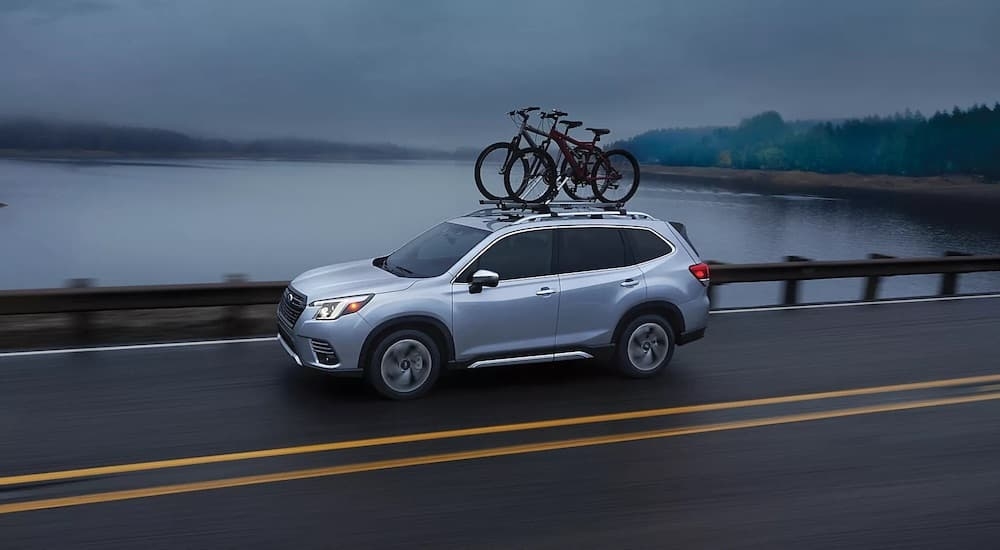 A silver 2024 Subaru Forester is shown from the side while hauling a pair of bikes.