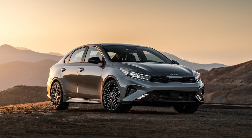 A grey 2024 Kia Forte GT parked on a hill at sunset.