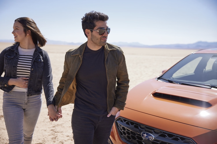 Coupe in desert walking around their new Subaru car