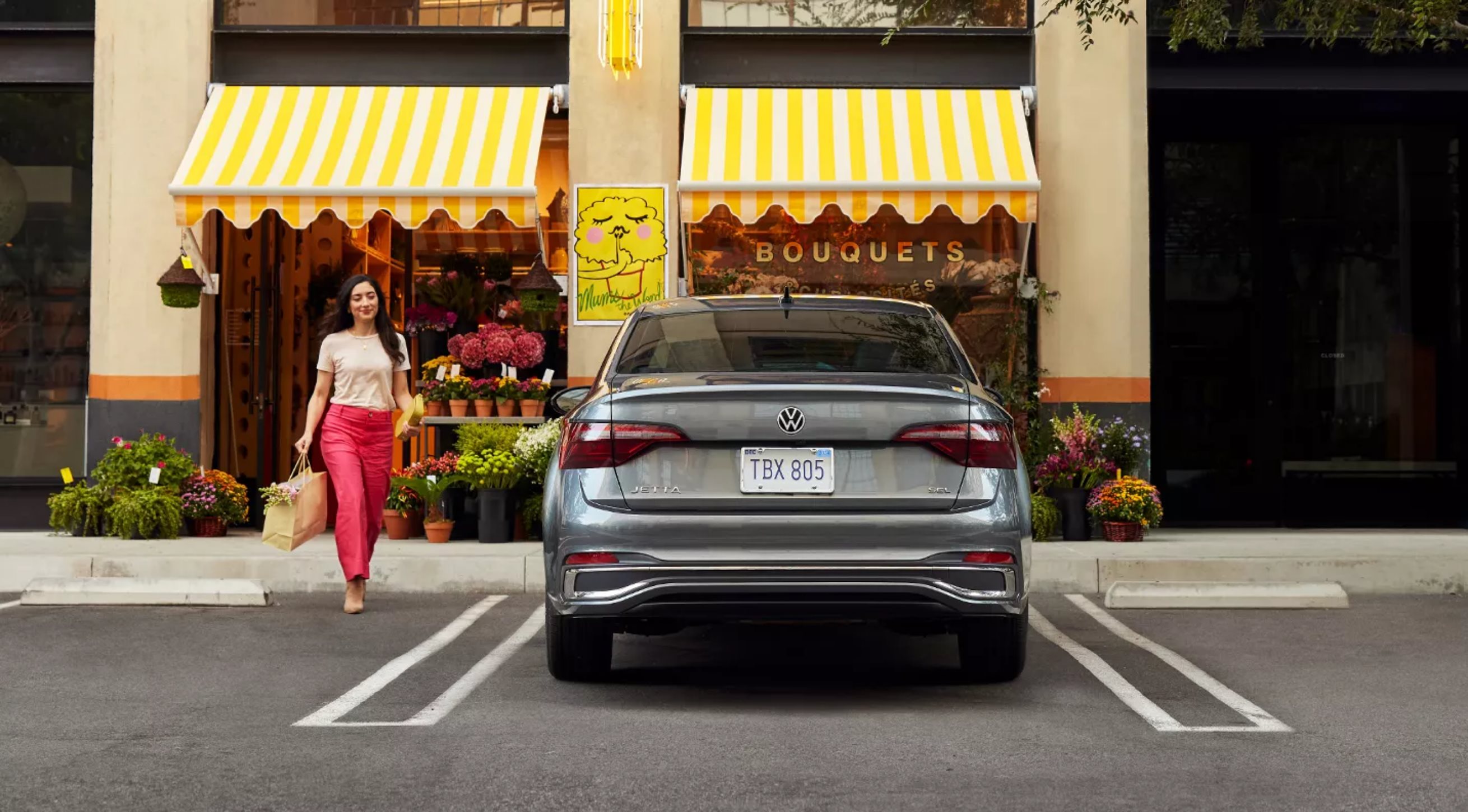 2024 Volkswagen Jetta parked in front of shop with woman approaching car.