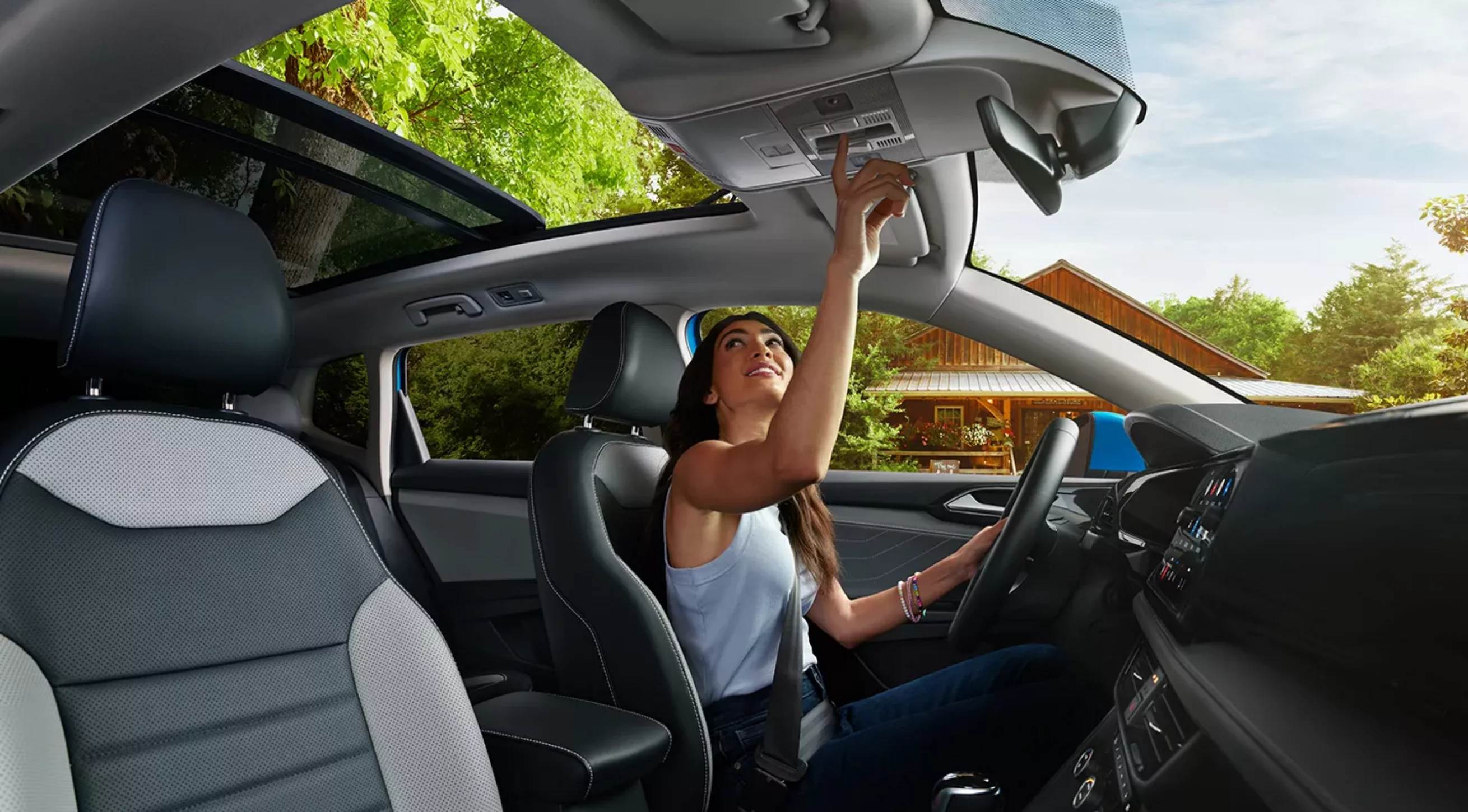 2024 Volkswagen Taos interior with woman operating sunroof.
