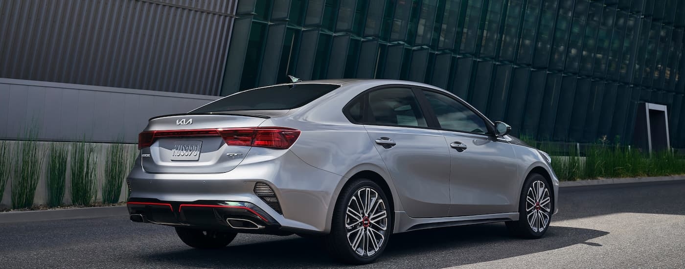 A grey 2022 Kia Forte GT is shown from a rear angle driving on a city street.