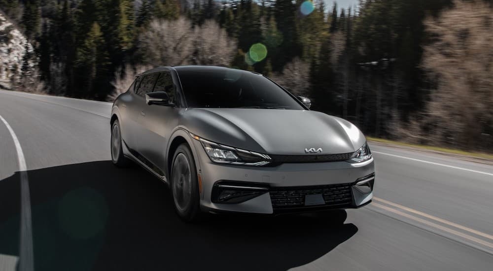 A grey 2021 Kia EV6 driving on a curving road.