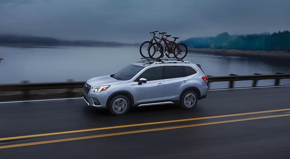 A silver 2024 Subaru Forester is shown from the side while with bikes loaded onto the roof.