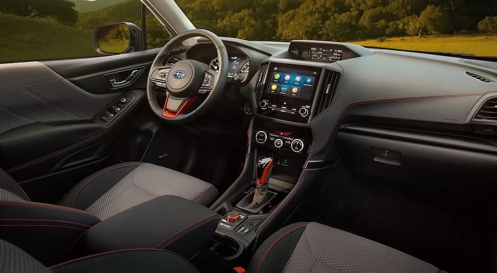 The black interior of a 2024 Subaru Forester is shown from the passenger side.