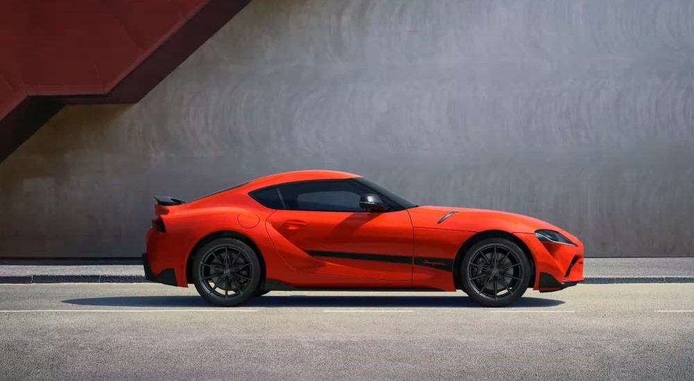 An orange 2024 Toyota GR Supra 45th Anniversary Edition is shown from the side after leaving a Toyota dealer.