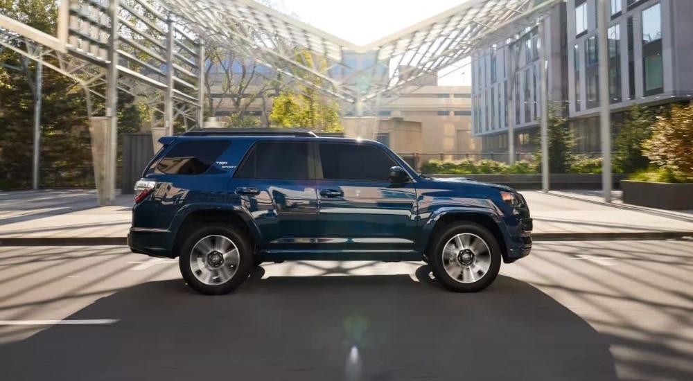 A blue 2024 Toyota 4Runner TRD Sport is shown driving on a city street.