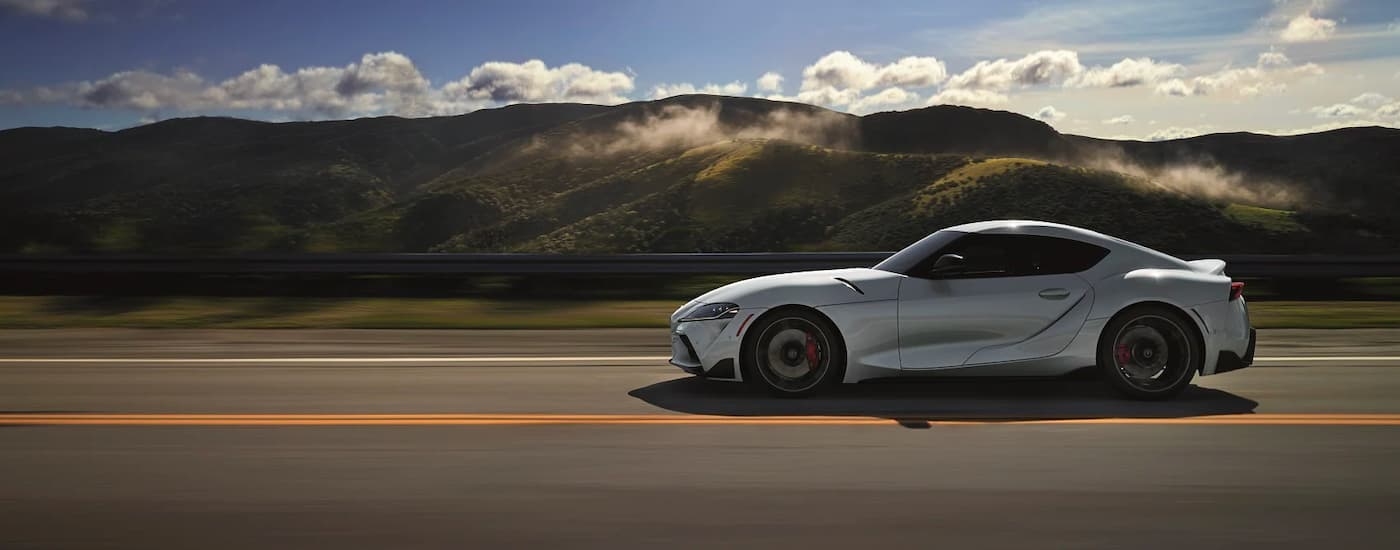 A white 2020 Toyota GR Supra is shown from the side driving on a cloudy day.