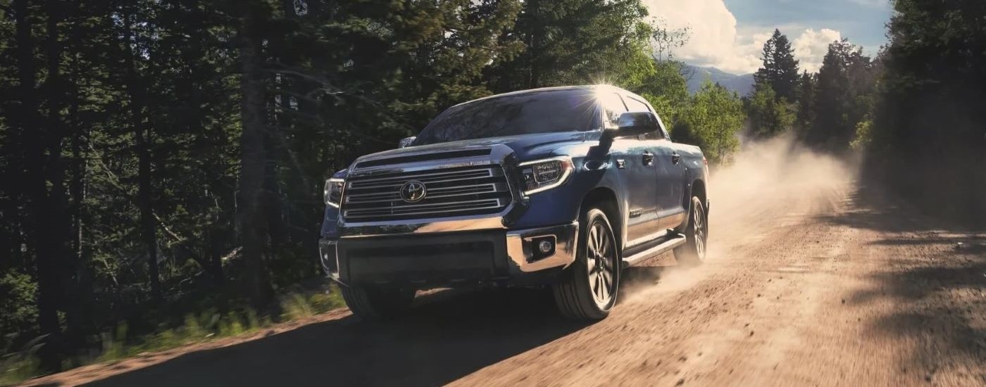 A blue 2020 Toyota Tundra is shown driving on a dusty trail after leaving a used Toyota dealer.