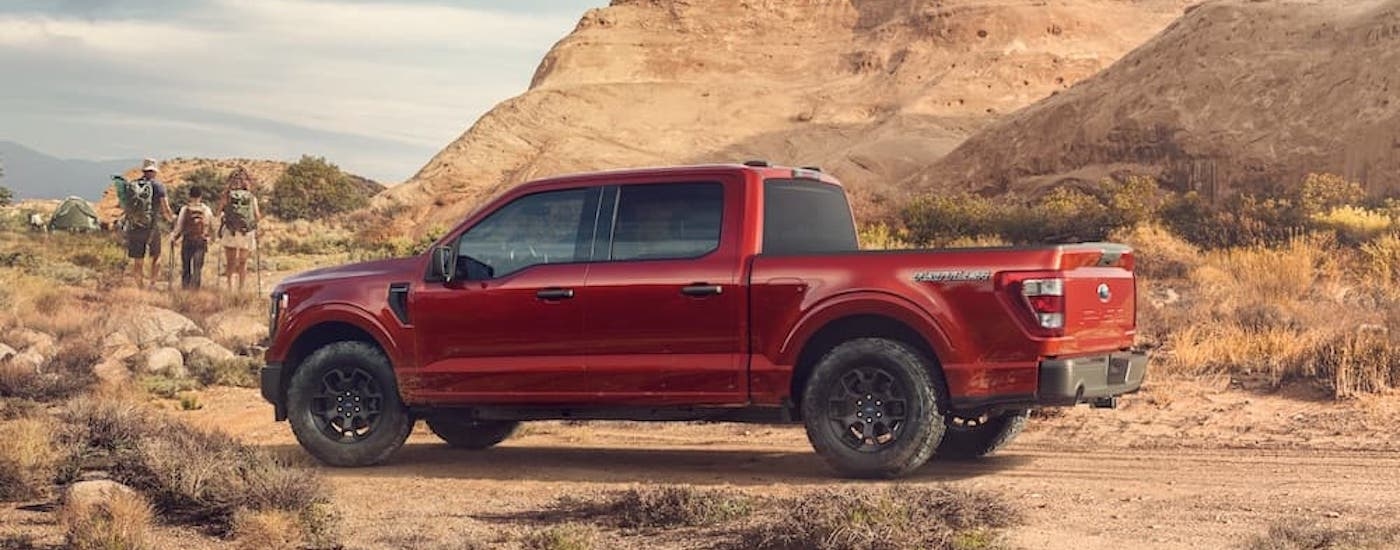 A red 2023 Ford F-150 Rattler is shown from the side while parked off-road.