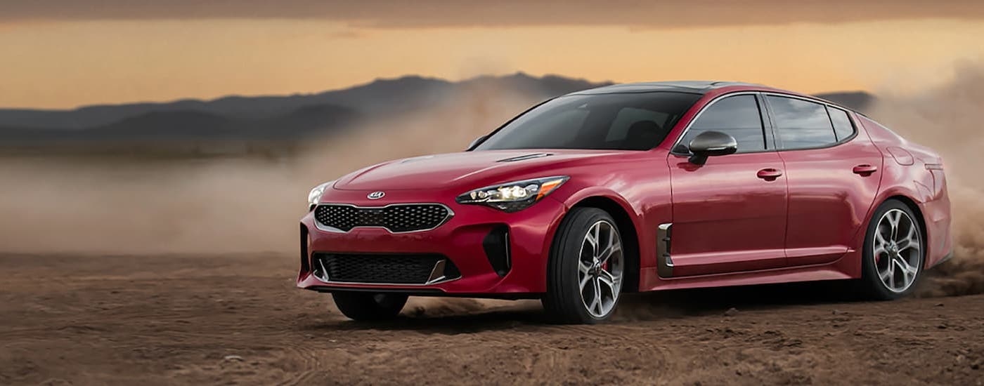 A red 2021 Kia Stinger is shown from the front while drifting on dirt after leaving a dealer that sells used cars in Victoria.