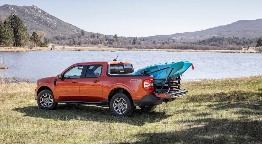 An orange 2024 Ford Maverick is shown from the rear at an angle while hauling a kayak.