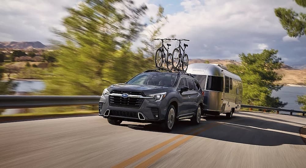 A grey 2024 Subaru Ascent is shown from the front at an angle while loaded with bikes and towing a camper.