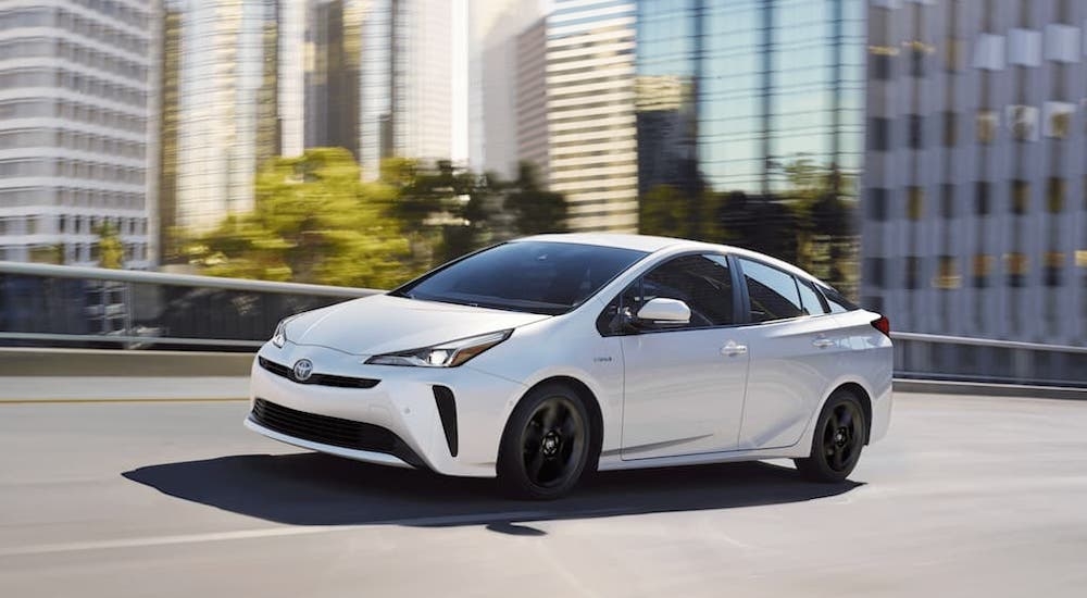 A white 2020 Toyota Prius is shown from the side on a city street.