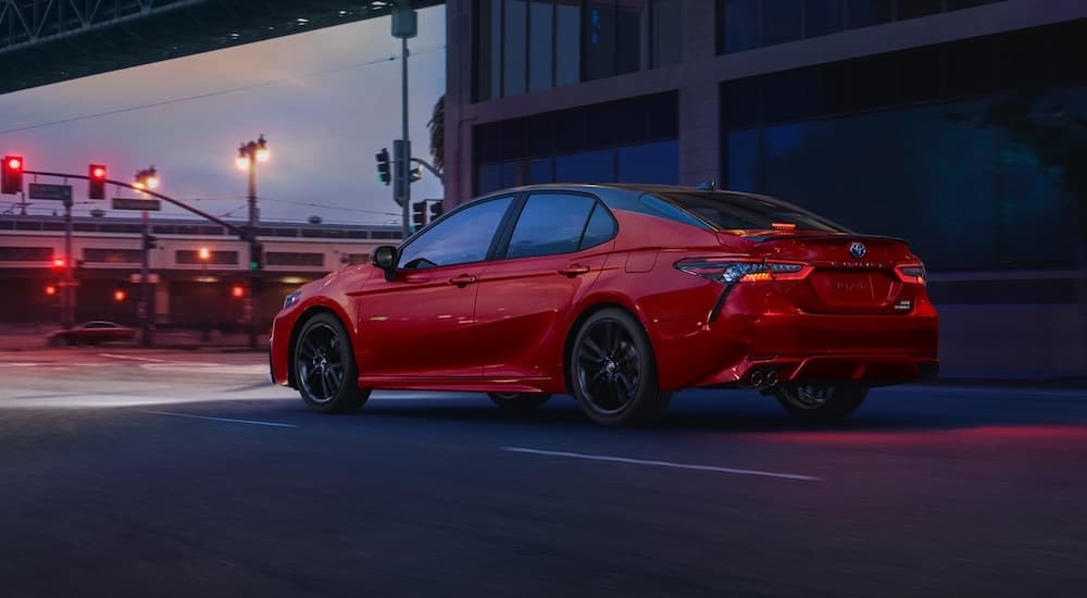 A red 2023 Toyota Camry is shown from the rear at an angle.