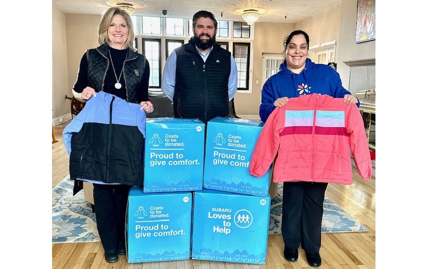 A group of Ruge's Subaru employees standing with boxes of donated coats.