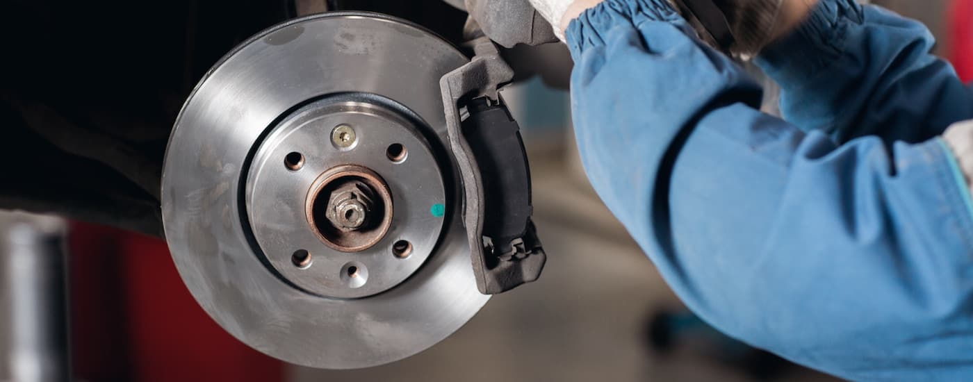 A mechanic is shown working on a brake caliper.