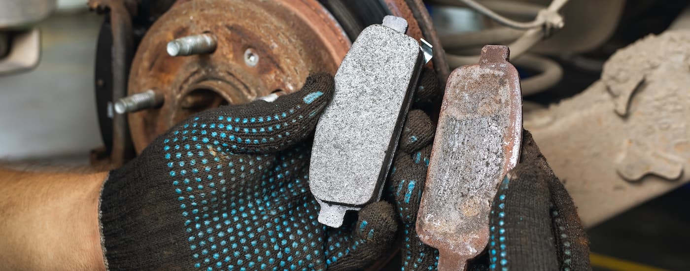 A mechanic is shown holding a new and an old brake pad.