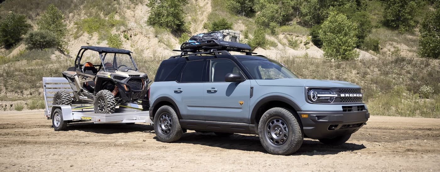 A blue 2024 Ford Bronco Sport Badlands is shown from the side while towing a UTV.