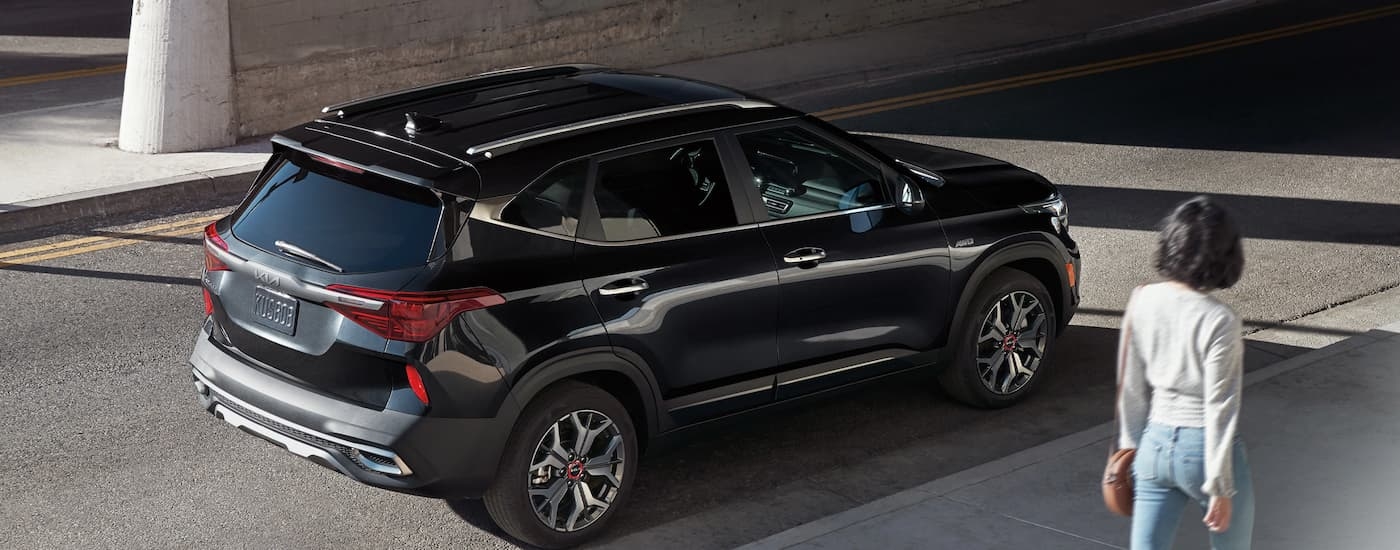 A black 2023 Kia Seltos is shown parked on the side of a city street.