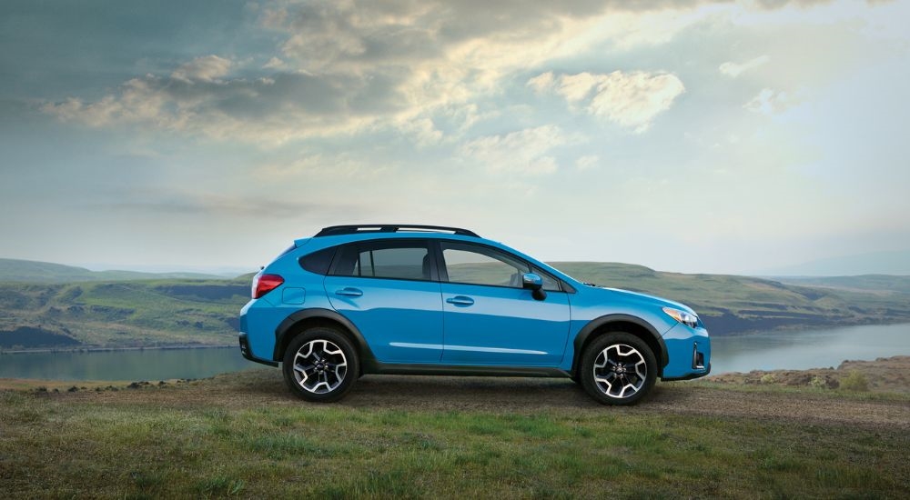 A blue Subaru Crosstrek is shown from the side overlooking a river.