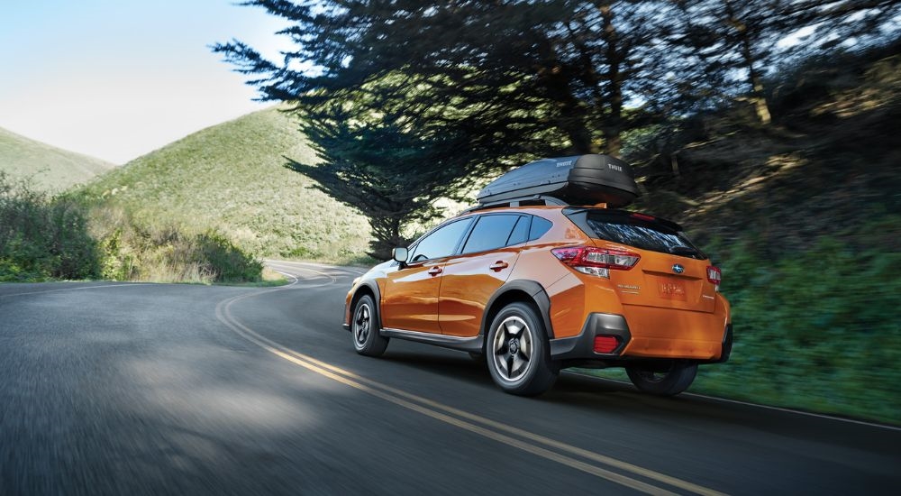 An orange 2020 Subaru Crosstrek Premium is shown on a winding road after leaving a used Subaru dealership near Poughkeepsie.