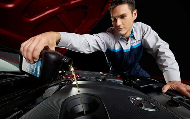 University Mazda service technician checking tire pressure during maintenance in Albuquerque