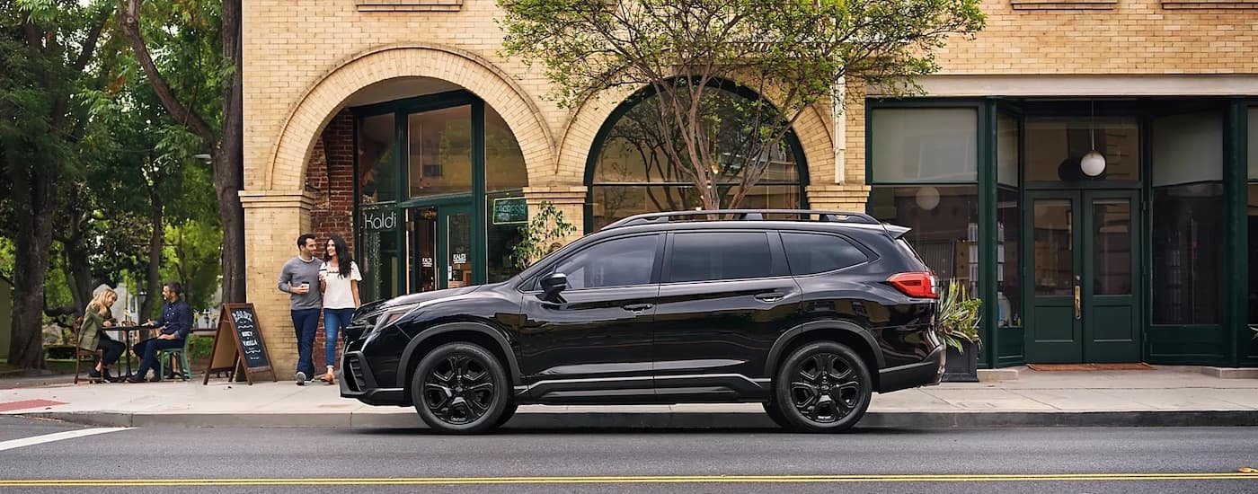 A black 2024 Subaru Ascent is shown from the side on a city street.