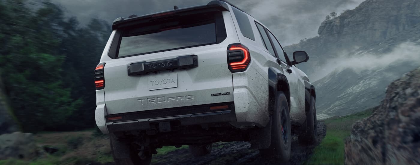 A white 2025 Toyota 4Runner TRD Pro is driving on a rocky trail near a mountain.