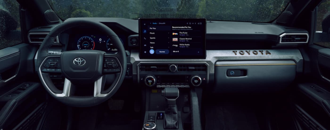 The steering wheel and infotainment screen in the black and silver accented interior of a 2025 Toyota 4Runner.