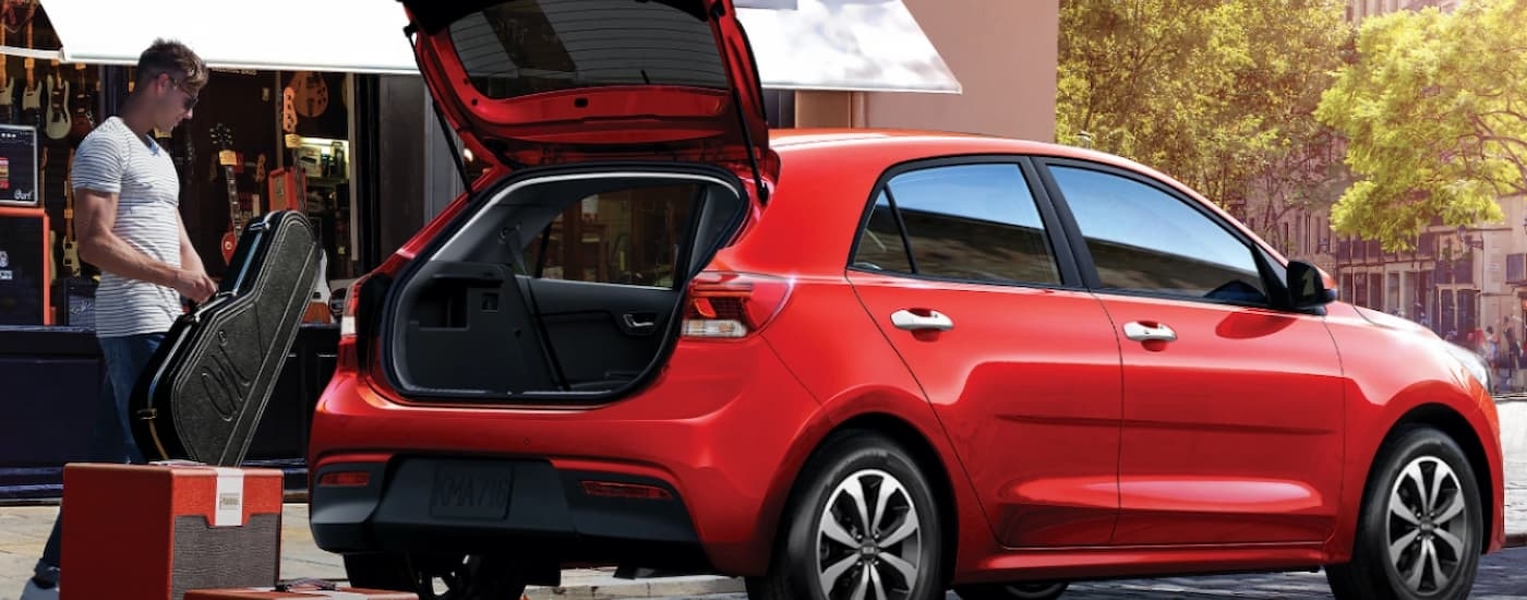 A red 2023 Kia Rio is loaded with a guitar and music gear.