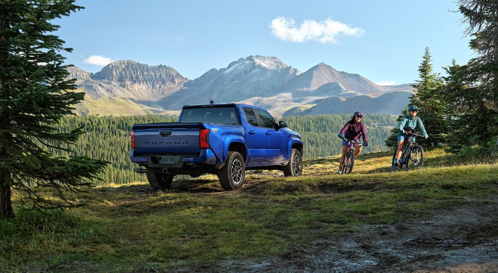 A blue 2024 Toyota Tacoma TRD Sport for sale is parked with a mountain view.