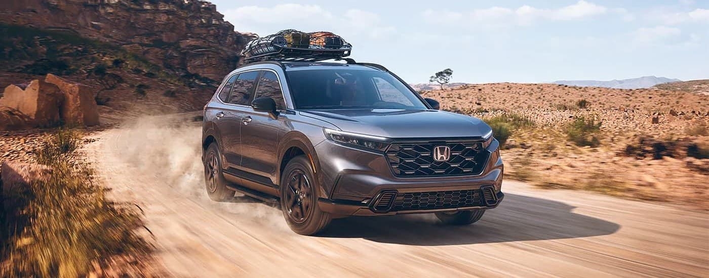 A grey 2023 Honda CR-V for sale is shown from the front at an angle while off-road.