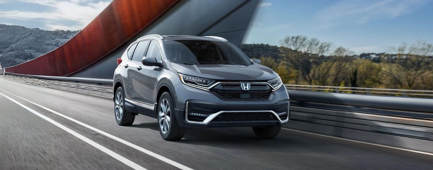 A grey 2020 Honda CR-V Hybrid is shown from the front at an angle while crossing a bridge.