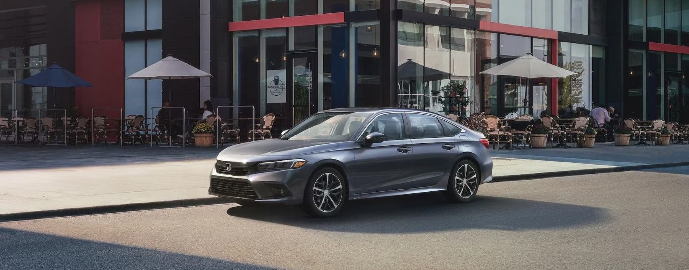 A grey 2024 Honda Civic is shown parked outside of a cafe.