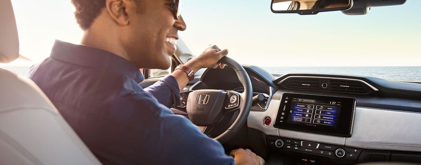 A person is shown smiling and steering a 2017 Honda Clarity Fuel Cell.