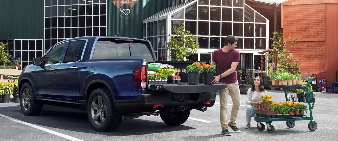 The bed of a blue 2023 Honda Ridgeline is shown being loaded with plants.