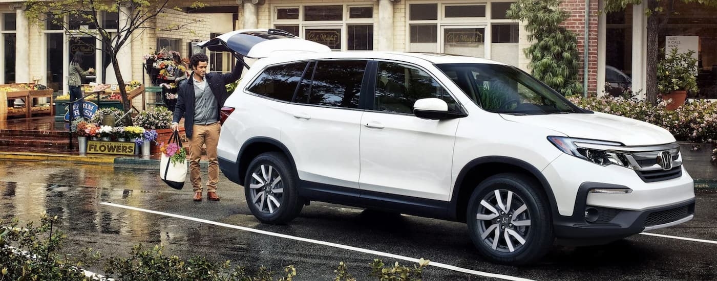 A white 2022 Honda Pilot parked in front of a flower stand.