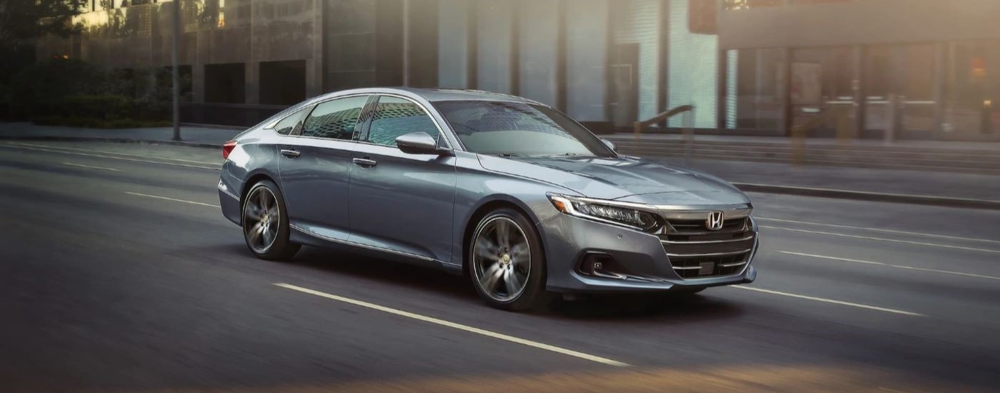 A silver 2021 Honda Accord Touring driving through the city to a used car dealership near Union City.