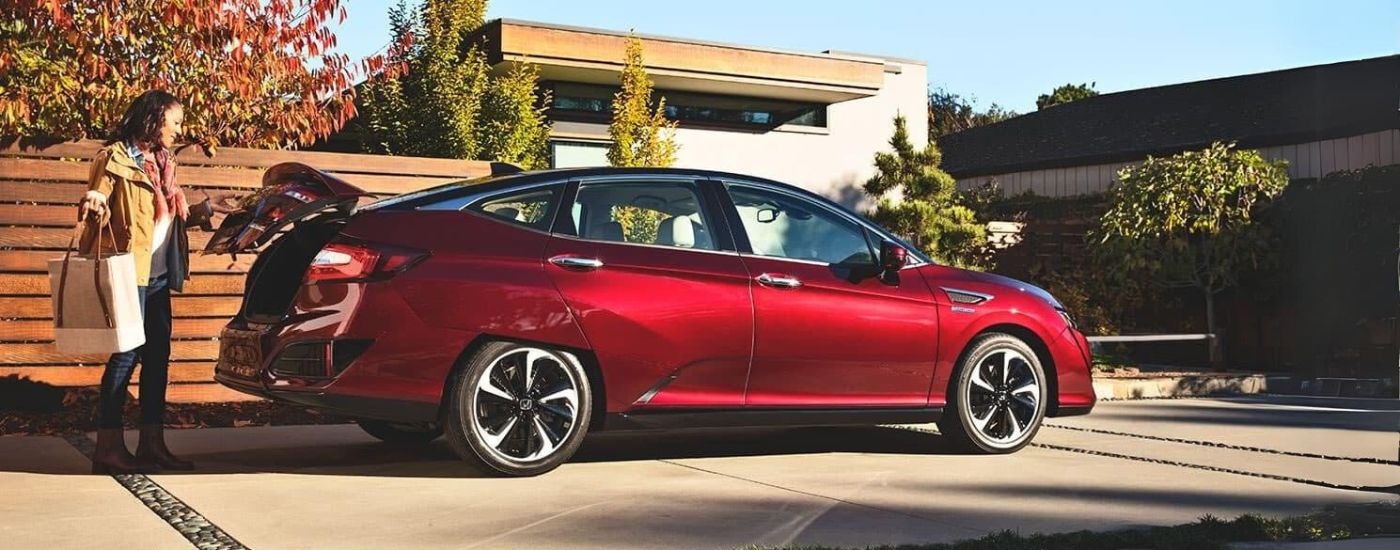 A person is shown loading a bag into a red 2017 Honda Clarity Fuel Cell EX.