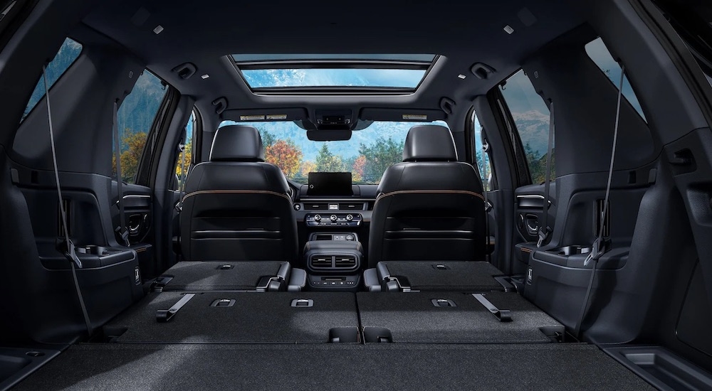 The black interior of a 2024 Honda Pilot TrailSport is shown from the rear with the liftgate open.