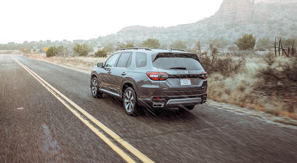 A grey 2024 Honda Pilot is shown from the rear at an angle.