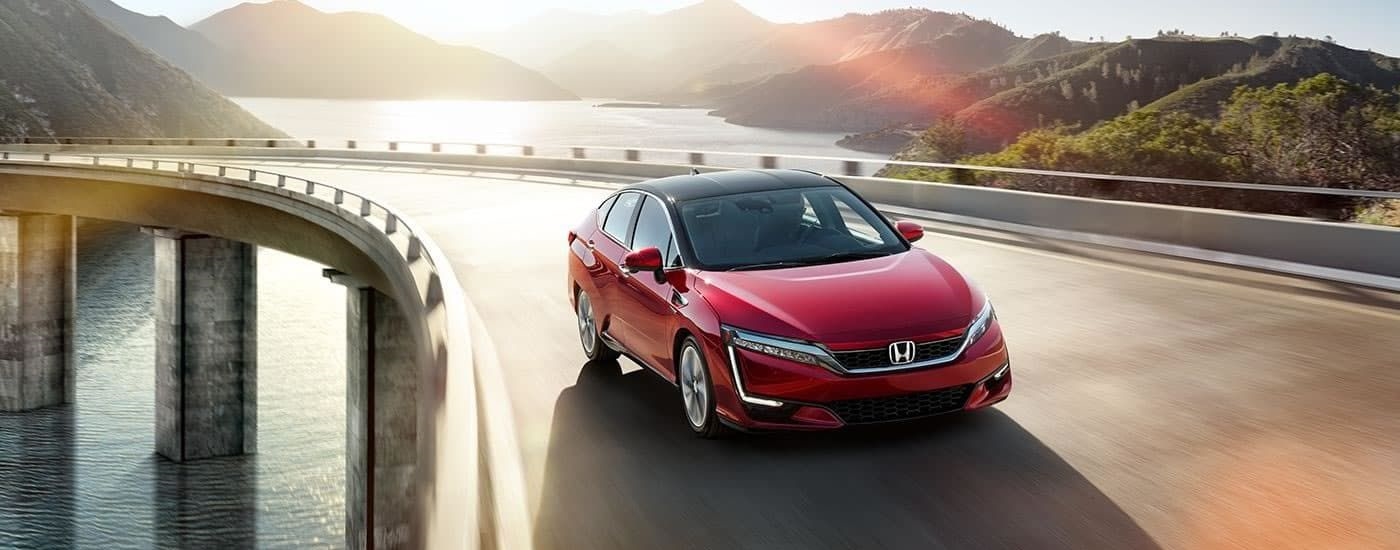 A red 2017 Honda Clarity Fuel Cell EX is shown driving on a bridge after visiting a used Honda dealership.