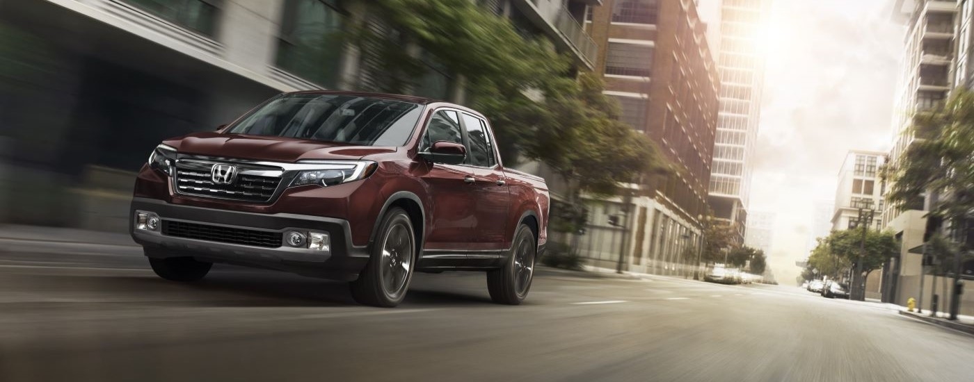 A maroon 2020 Honda Ridgeline RTL-E driving on a city street.