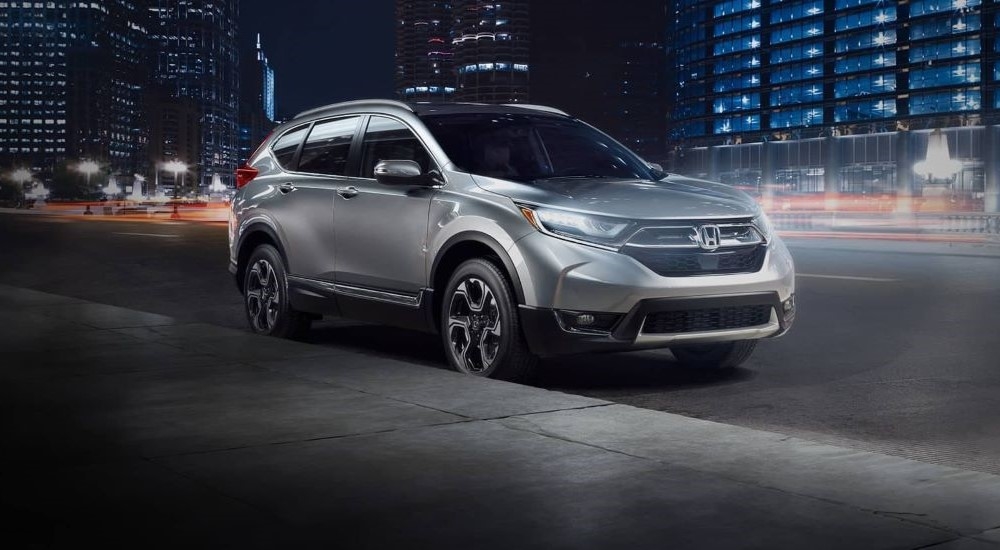 A silver 2017 Honda CR-V Touring is shown on a city street at night.