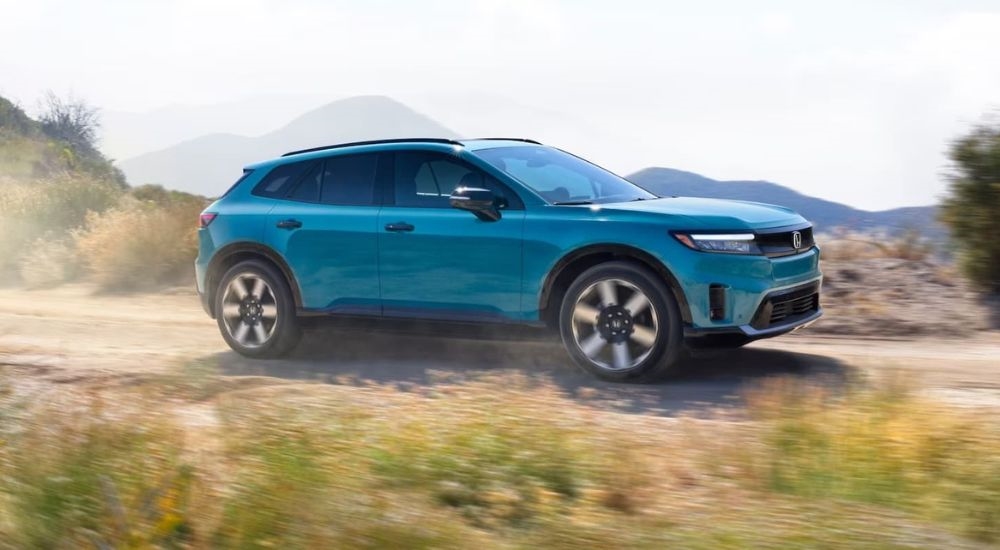 A teal 2024 Honda Prologue is shown from the side while off-road.
